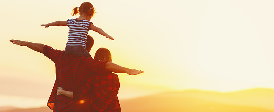 Familia feliz: madre padre e hija en la naturaleza al atardecer